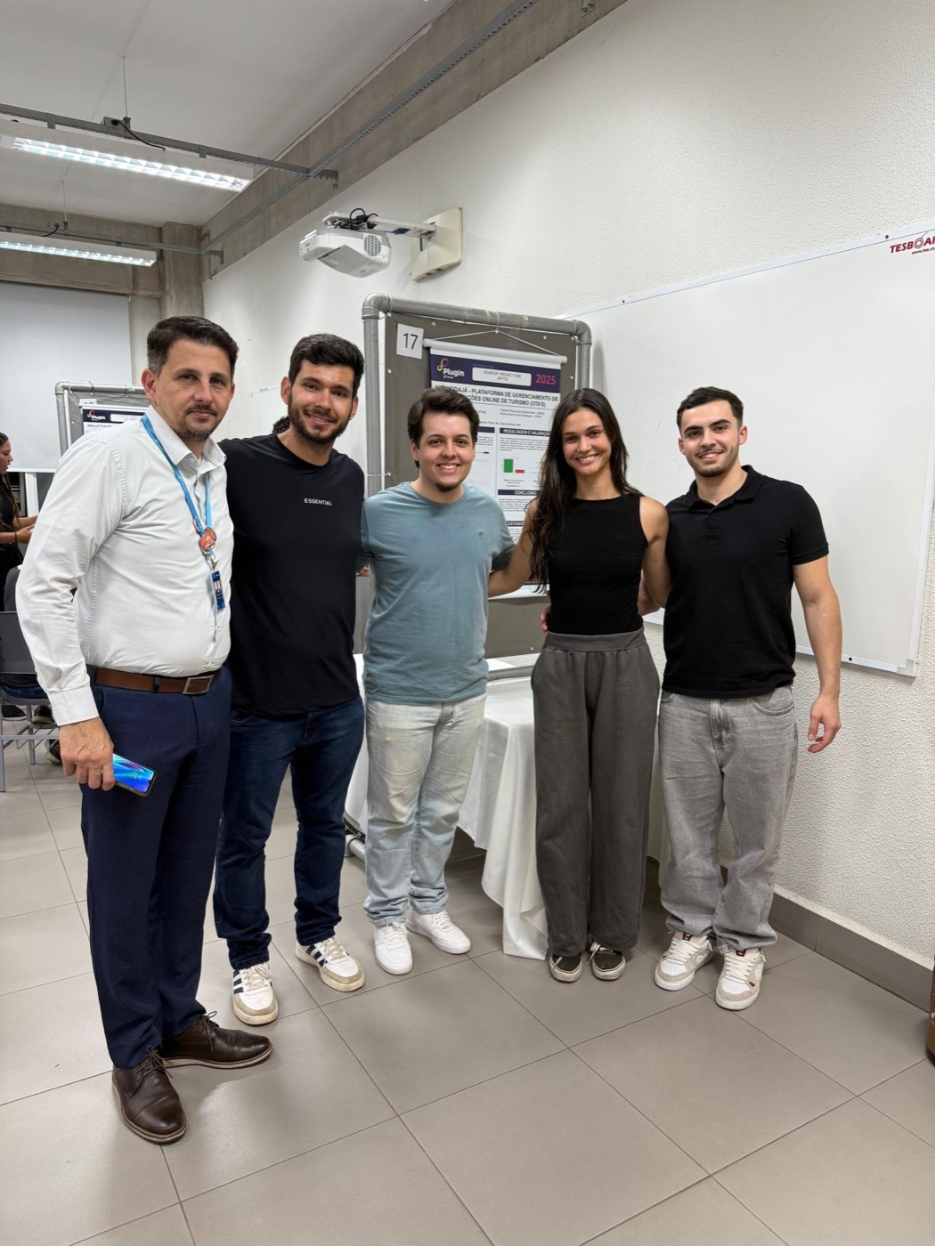 The AcomodaJá team next to the project poster at the Plugin 2025 showcase