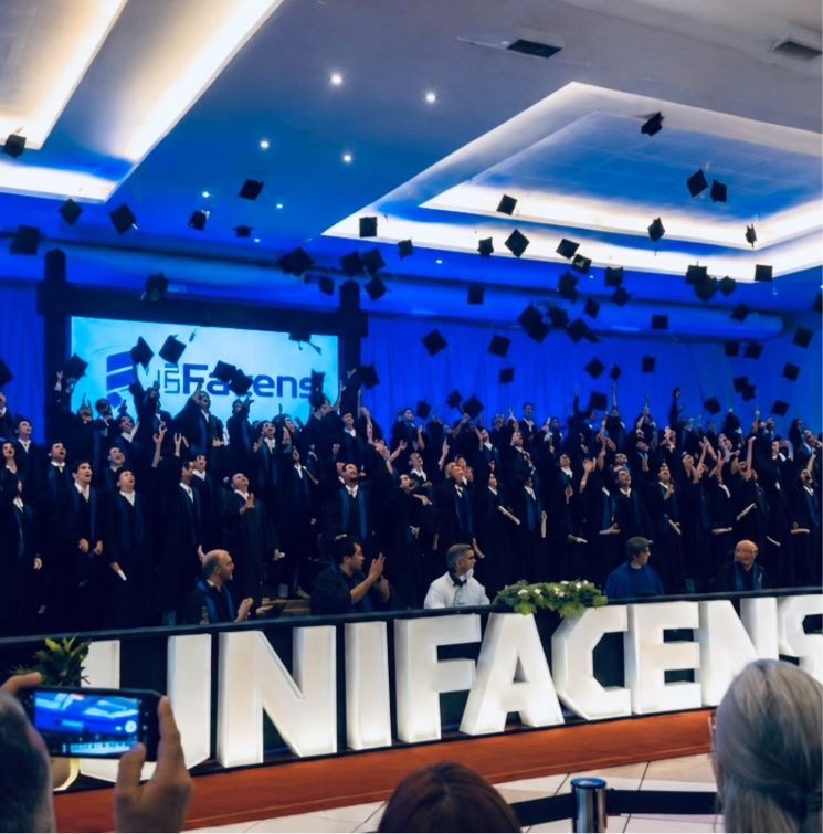 Graduation ceremony at UNIFACENS, graduates throwing their caps in the air